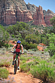 Woman rides the Templeton Trail in South Sedona, Arizona.  Templeton Trail rides over slickrock of the Cathedral Rock with views of Courthouse Butte across the way.