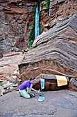 Female hiker filters water on a cliff-pinched patio near Deer Creek Falls in the Grand Canyon outside of Fredonia, Arizona November 2011.  The 21.4-mile loop starts at the Bill Hall trailhead on the North Rim and descends 2000-feet in 2.5-miles through Co