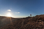 Girl doing yoga on the top of a volcano at sunset in Fuerteventura, Canary Islands
