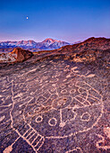 Piute Petroglyphs and full moon at sunrise with snow-capped Sierra in background, Eastern Sierra, California