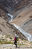 A woman is hiking toward a river, Spiti, India.