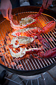 Putting halved lobsters on a charcoal grill.