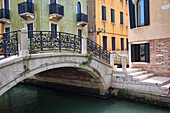 A quaint bridge over a small canal with colourful buildings, Venice, Italy