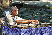 Man selling carvings of the ancient tales and the Ramayana epic in Sanskrit on lontar leaves, Tenganan Pegringsingan, Bali, Indonesia