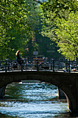 Woman on bicycle crossing bridge early in the morning, Amsterdam, Holland