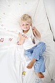 Little boy lying down on his bed reads a book