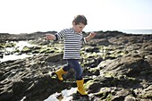 3 years old boy playing in the rocks near the beach