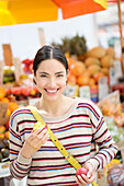 Hispanic woman eating fruit at farmers market