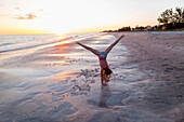 Caucasian girl doing cartwheels on beach