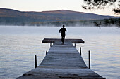 Businessman in Suit and Hat Running Down Lakeside Dock