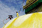 Männer mit gelber Farbe auf der Swayambhunath Stupa in Kathmandu, Nepal, Asien