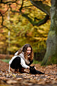 Girl stroking a black cat in an Autumn forest, Hamburg, Germany, Europe