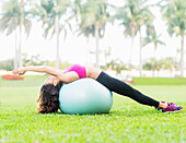 Chinese woman stretching on fitness ball in park