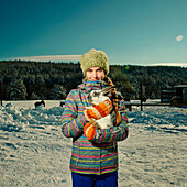 Caucasian girl hugging rabbit in snowy field