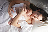 Mother sleeping with newborn baby on bed