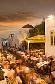Time lapse view of tourists eating in sidewalk cafe at sunset, Mykonos, Cyclades, Greece