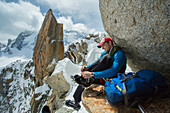 Caucasian hiker fastening ice cleats on rocky mountain, Chamonix, Haute-Savoie, France