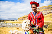 Hispanic girl walking llama in rural landscape