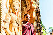 Asian monk-in-training peering around carved temple walls