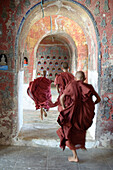 Asian monks-in-training running in dilapidated temple hallway