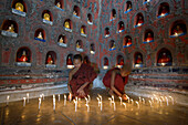 Asian monks-in-training lighting candles in ancient temple