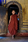 Asian monk-in-training walking out of temple archway