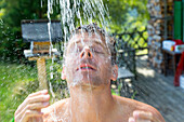 Mann duscht in der Freiluftdusche, Alm, Urlaub, Berghütte, MR, Maria Alm, Berchtesgadener Land, Alpen, Österreich, Europa