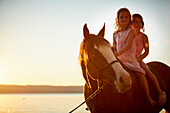 Two girls riding a quarter horse near Lake Starnberg, Upper Bavaria, Bavaria, Germany