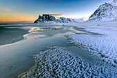 Dawn illuminates the beach covered with frozen snow in the cold sea of Uttakleiv, Lofoten Islands, Arctic, Norway, Scandinavia, Europe
