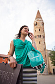 Woman with shopping bags at the bell tower, Campanile von Caorle, Caorle, Venice, Veneto, Italy
