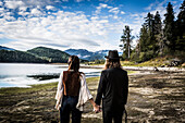 1970s Styled Couple Looking at Scenic Landscape, Rear View, Merrill Lake, Washington, USA