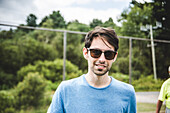 Young Adult Man in Sunglasses Smiling Outdoors