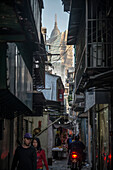 man on motorbike drives through narrow alley towards Grad Lisboa Casino, Macao, China, Asia
