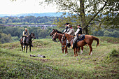 Five American Civil War confederate re-enactors sitting on horses and discussing the battle with a railroad bridge in the background, United States of America