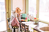 Caucasian woman paying bills on telephone in kitchen