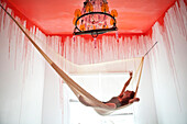 Caucasian woman laying in hammock under dripping ceiling