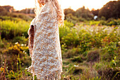 Woman wrapped in blanket walking in field