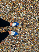 Caucasian woman wearing sneakers in pebbles