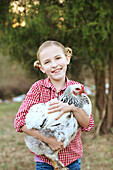 Caucasian girl holding chicken on farm