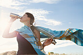 Caucasian woman drinking from bottle in wind