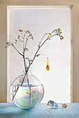 Glass ornament hanging from plants in glass vase