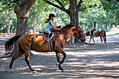Equestrian girl riding horse on ranch