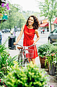 Mixed race woman pushing bicycle on city sidewalk
