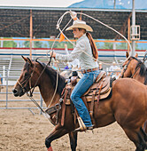 Caucasian cowgirl twirling lasso in rodeo