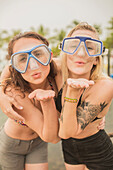 Caucasian women blowing kisses in snorkel masks