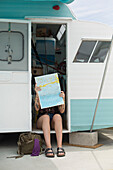 Caucasian woman reading map in trailer