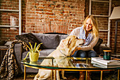 Caucasian woman petting dog in living room
