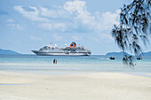 People on beach with expedition cruise ship MS Hanseatic Hapag-Lloyd Cruises at anchor, Amphoe Ko Kut, Trat, Thailand