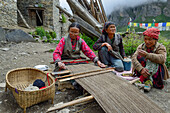 Women weaving on a simple weaving loom on the ground in Nar, Nepal, Himalaya, Asia