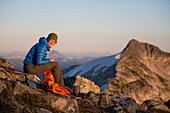 Portrait of a female backpacker preparing dinner on a rocky mountain ridge.
